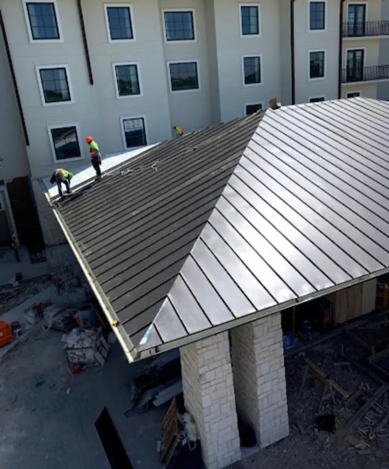 Crew installing standing seam metal roof panels on a commercial project in Alpine